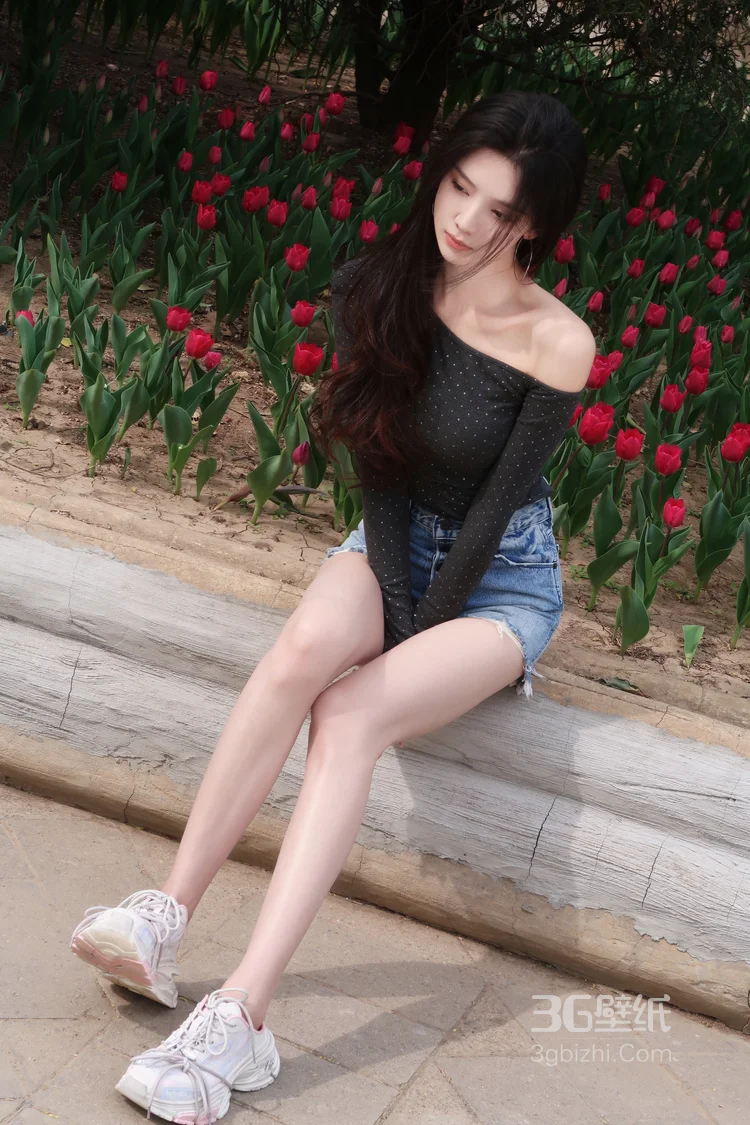 高颜值苗条美女黑色斜肩波点上衣、牛仔短裤穿着郁金香花丛旁超高清图片2