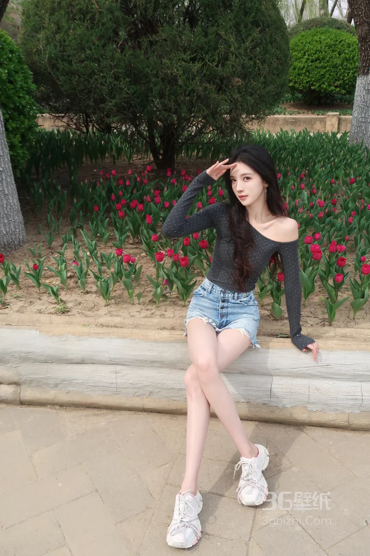 高颜值苗条美女黑色斜肩波点上衣、牛仔短裤穿着郁金香花丛旁超高清图片3