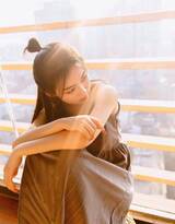 坐靠阳台的漂亮丸子头美少女咖色吊带裙穿搭写真照