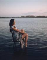 坐在湖中椅子上，手拿一盏油灯的欧美外国睡裙女人摄影艺术图片