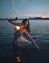 坐在湖中椅子上，手拿一盏油灯的欧美外国睡裙女人摄影艺术图片