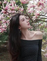 高颜值苗条美女黑色斜肩波点上衣、牛仔短裤穿着郁金香花丛旁超高清图片